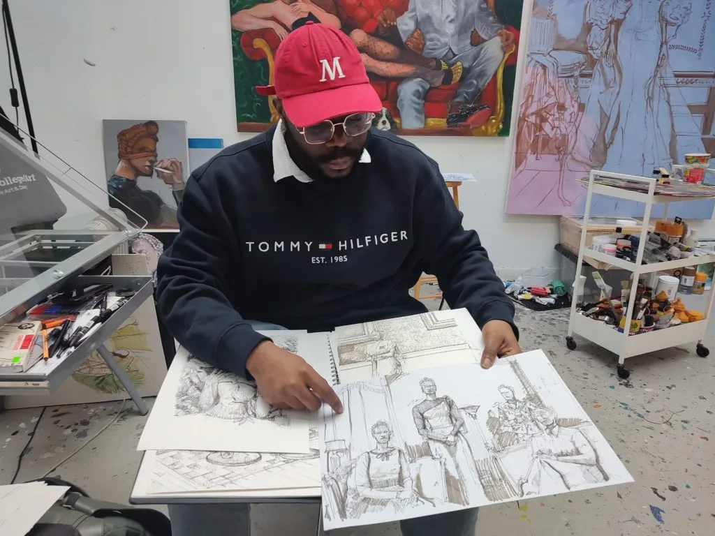 Tonye Ekine in his studio holding a sketchbook.