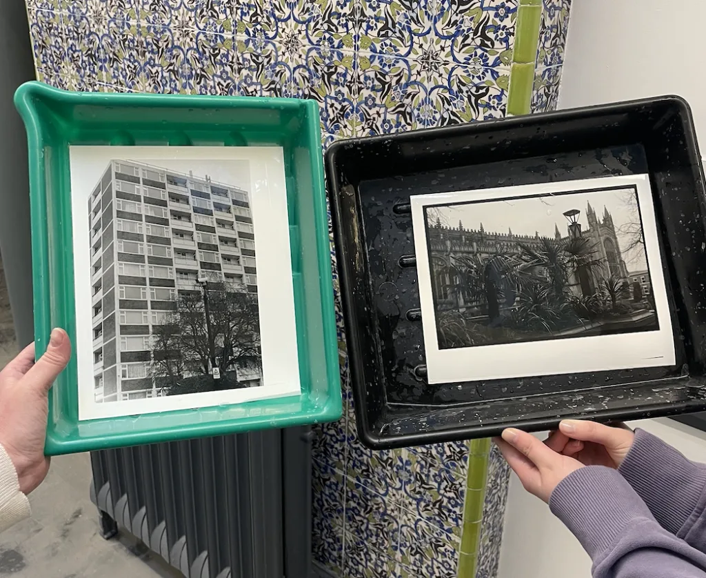 Two trays with black and white photographs made in our darkroom inside.