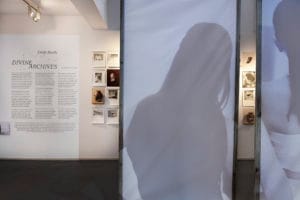 A wider photograph of the gallery with a paper room divider with projections of a short film by Emily Ryalls.