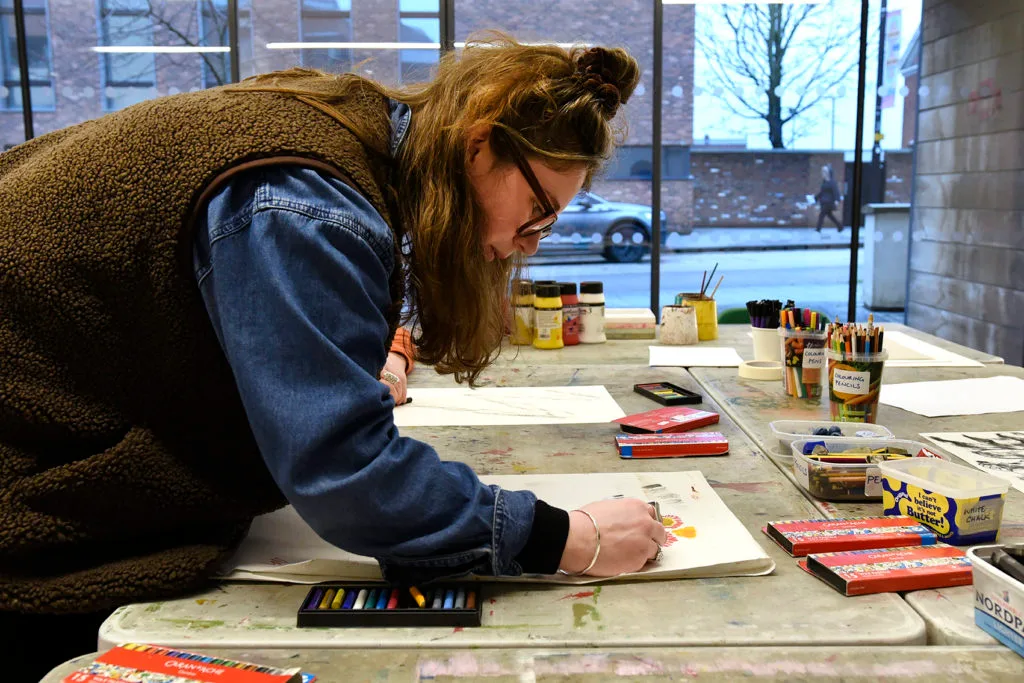 A woman drawing surrounded by art materials