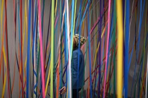 A person stood surrounded by colourful streamers