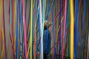 A person stood surrounded by colourful streamers