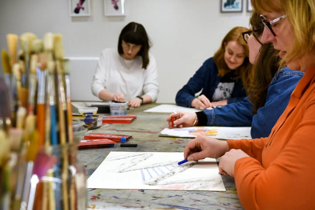 A group of people sat around a table with drawing materials