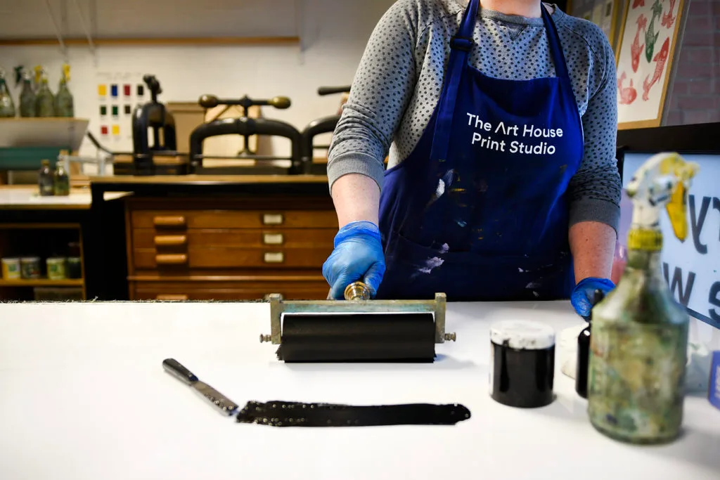 A woman rolling out a pad of black ink for printmaking