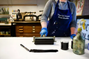 A woman rolling out a pad of black ink for printmaking