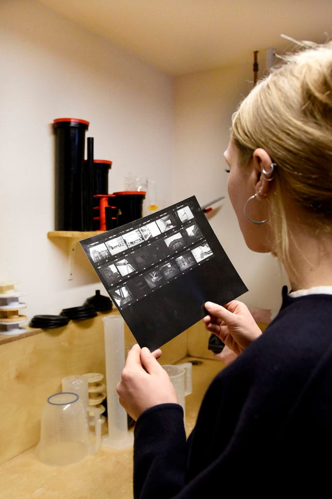 A woman looking closely at a darkroom contact sheet