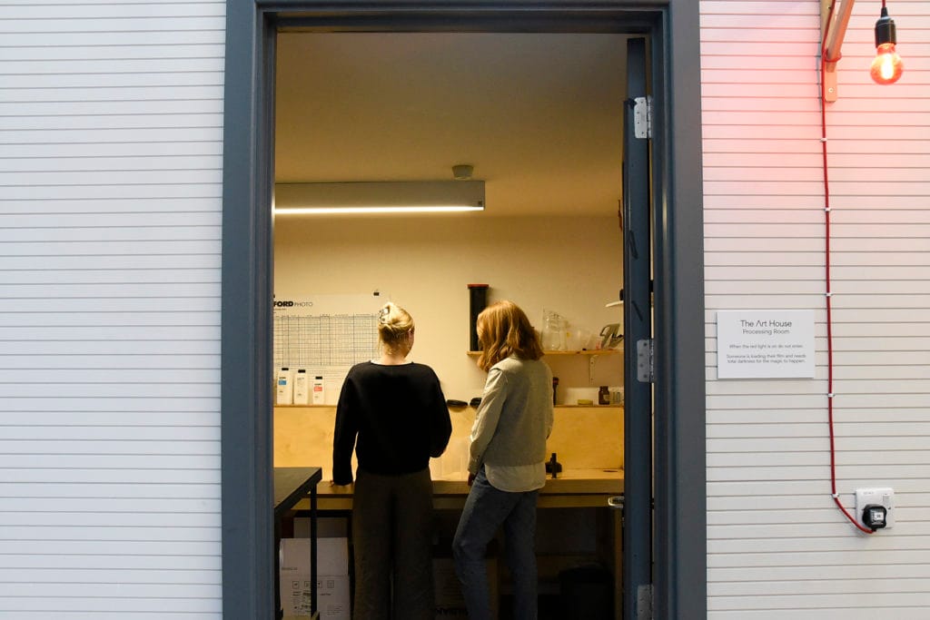 A view into the darkroom processing room with two women looking at the equipment